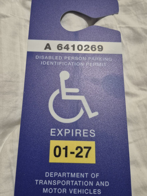 Blue disabled person parking permit card on a textured surface FL