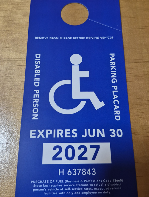 Blue disabled parking placard with expiration date on a glossy plastic surface Generic.